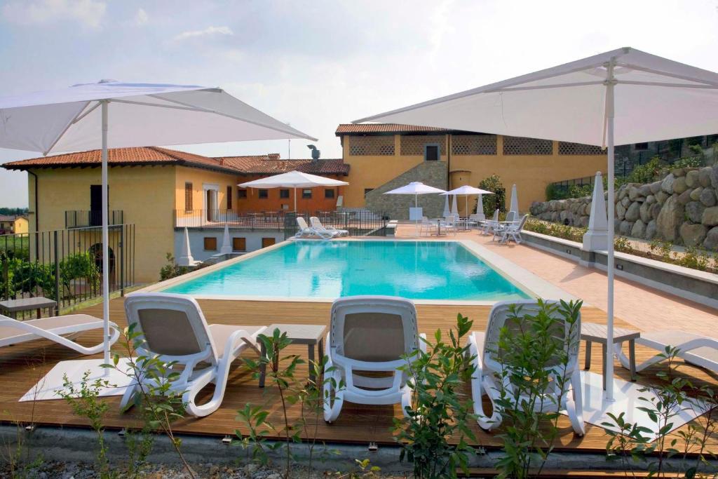 a swimming pool with chairs and umbrellas at Corte Lantieri in Capriolo