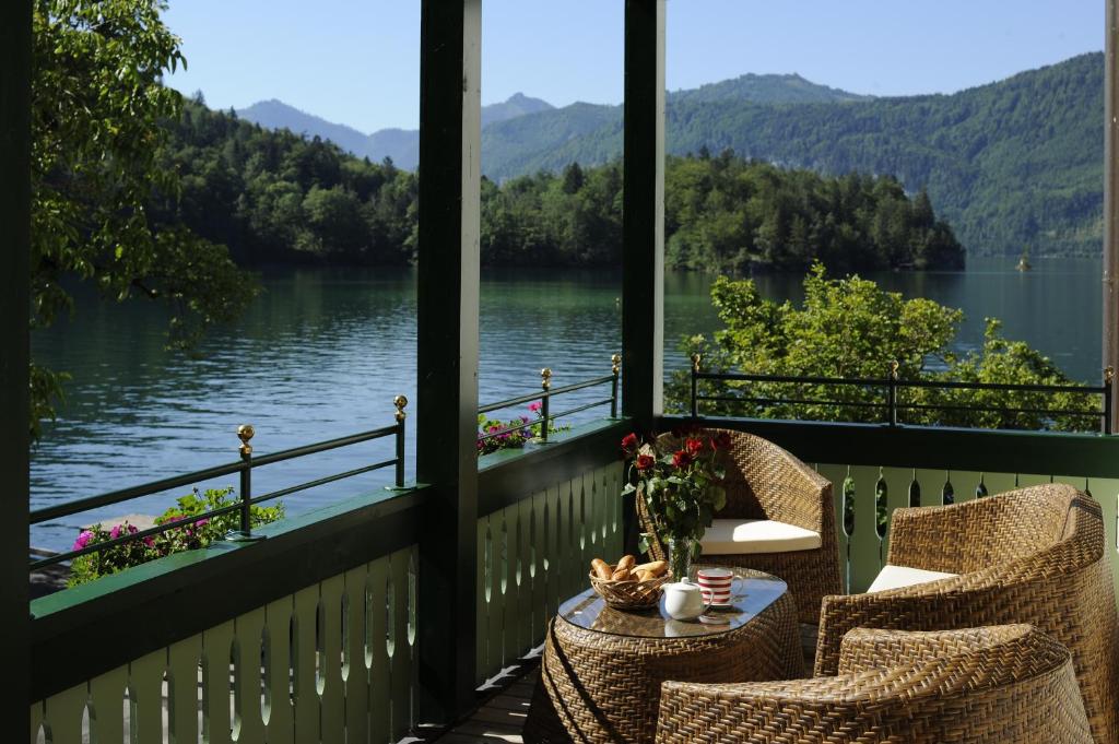 a porch with chairs and a table with a view of a lake at Hotel & Gasthof Fürberg in Sankt Gilgen