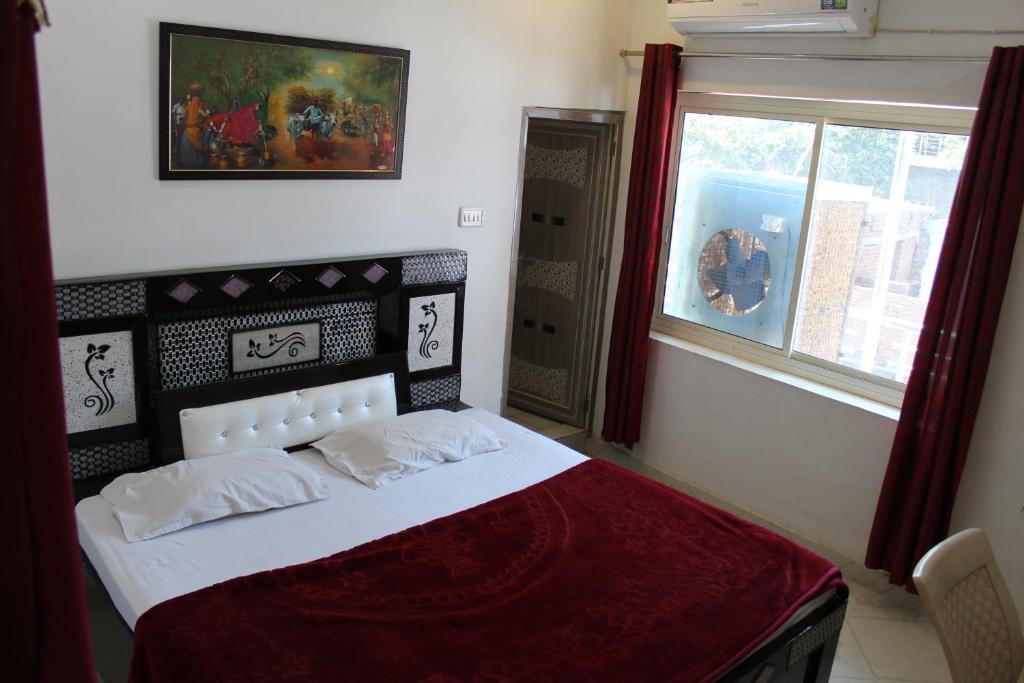 a bedroom with a bed with a red blanket and a window at Best B&B in Orchha in Orchha