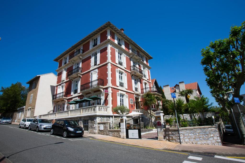 a red brick building with cars parked in front of it at Hôtel & Espace Bien-être La Maison du Lierre in Biarritz
