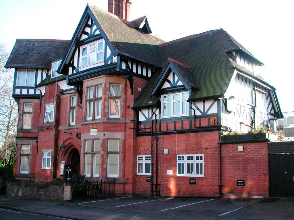 een groot gebouw van rode baksteen met een zwart dak bij Croft Hotel in Leicester