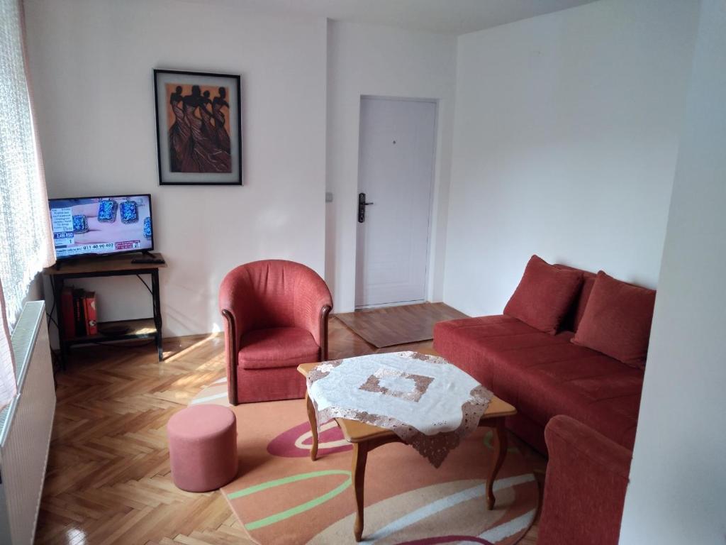 a living room with a red couch and a table at Sokobanja Apartmani in Soko Banja