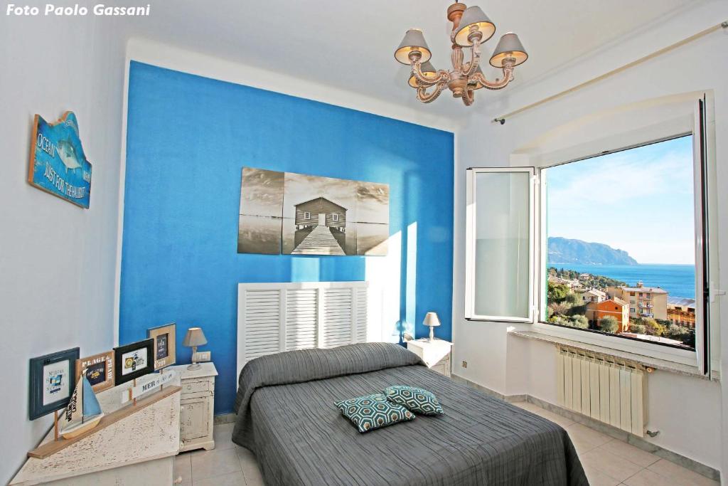 ein Schlafzimmer mit einer blauen Wand und einem großen Fenster in der Unterkunft Cav Gli Ulivi di Bogliasco in Bogliasco