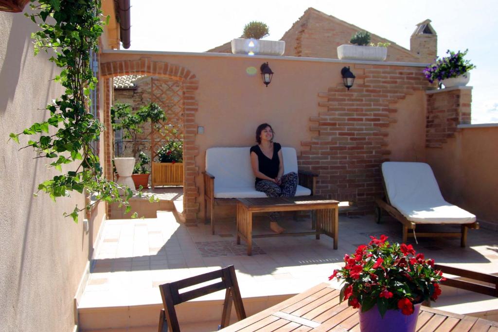una mujer sentada en una silla en un patio en B&B Le Terrazze Fermo, en Fermo
