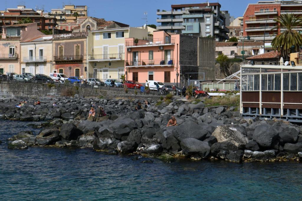 a group of people sitting on rocks in the water at Niria Home in Catania