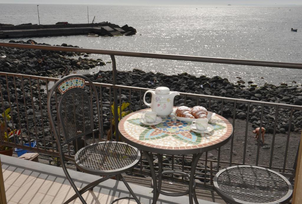 a table with a tea set on a balcony overlooking the water at Niria Home in Catania