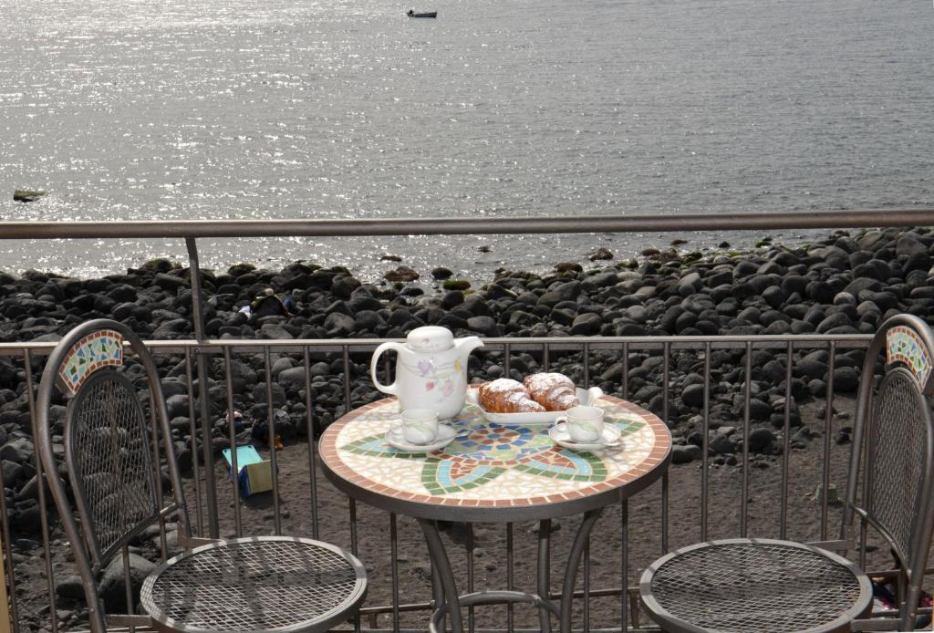 a table with a tea set on a balcony next to the ocean at Niria Home in Catania