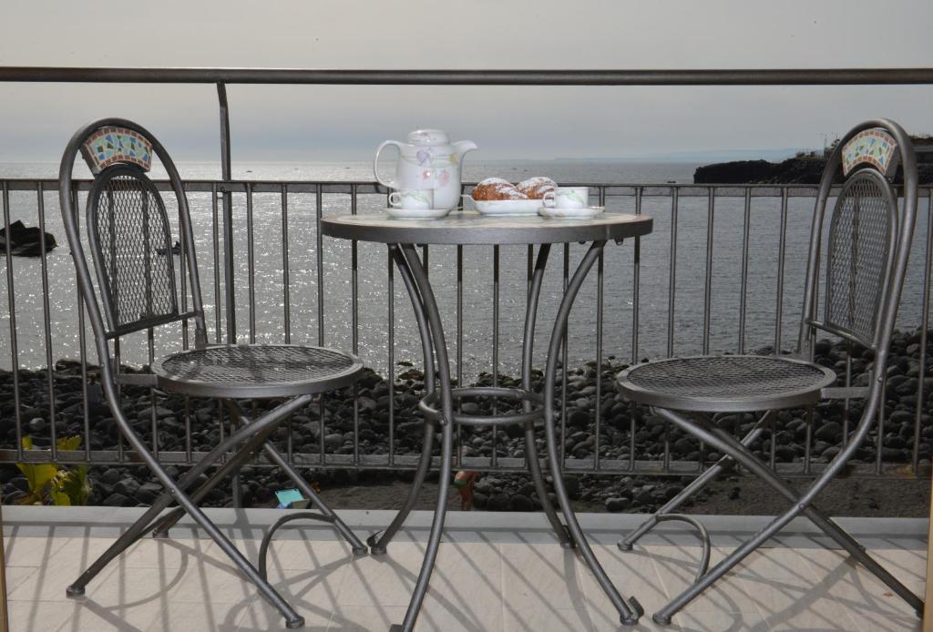 a table with two chairs and a tea set on a balcony at Niria Home in Catania