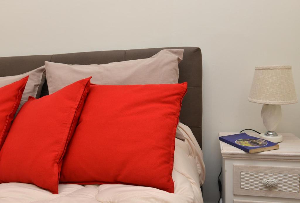 a bed with red pillows and a night stand with a lamp at Niria Home in Catania