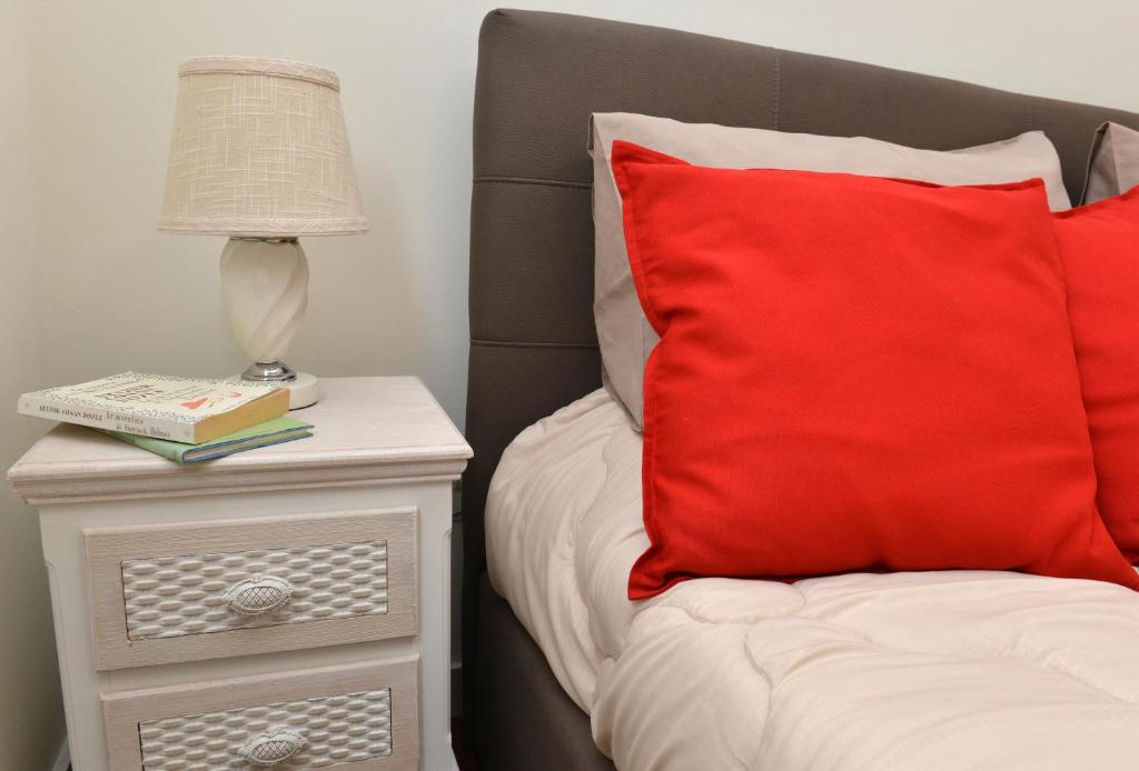 a bed with a red pillow and a nightstand with a lamp at Niria Home in Catania