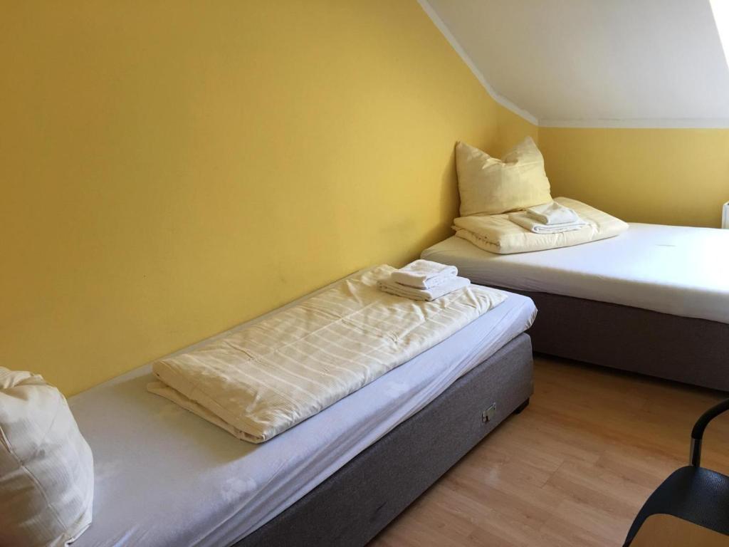 2 Betten in einem Zimmer mit gelben Wänden in der Unterkunft Zweibettzimmer in Kaiserslautern