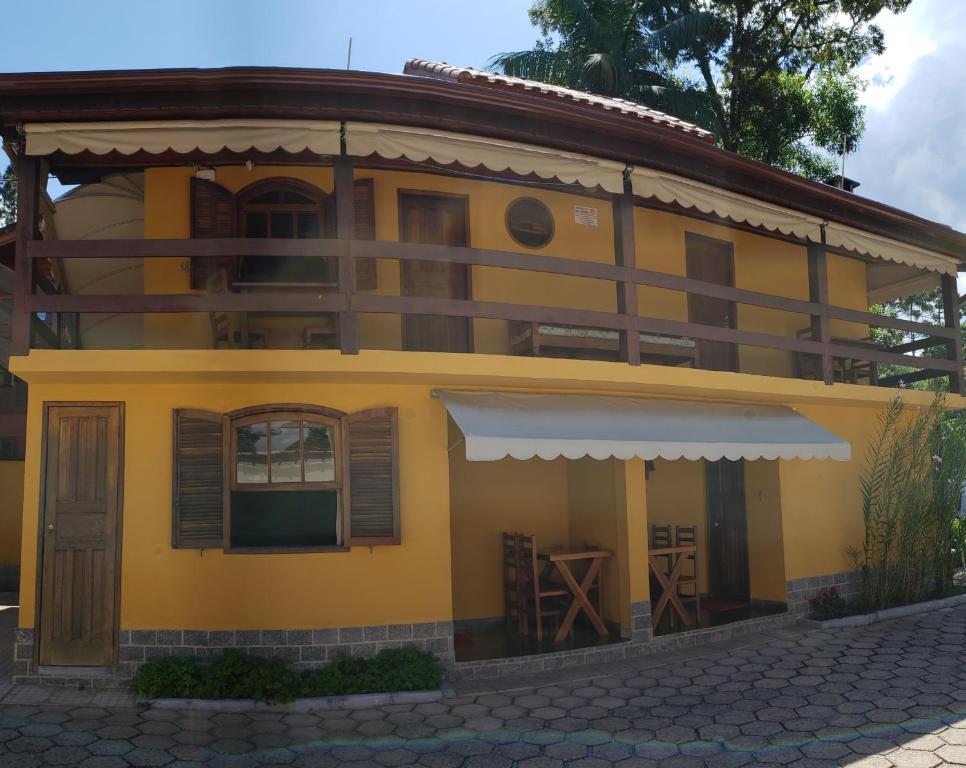 una casa amarilla con techo marrón en Pousada Verde Novo, en Visconde De Maua