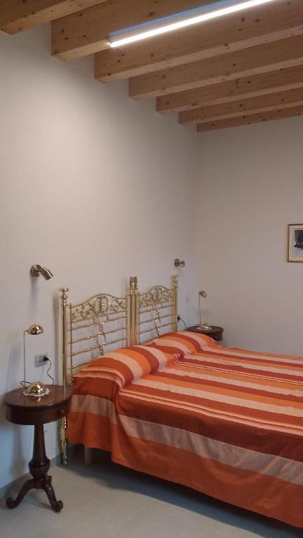 sypialnia z łóżkiem z pomarańczową pościelą i stołem w obiekcie Agriturismo Cascina Poscallone w mieście Abbiategrasso
