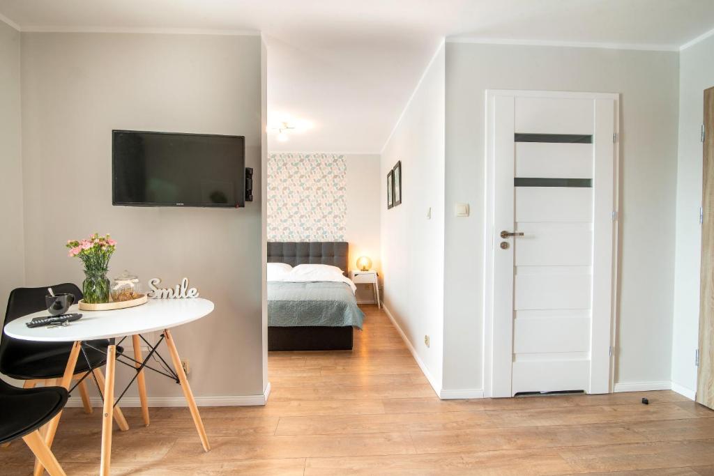 een klein appartement met een slaapkamer, een tafel en een bed bij LEŚNA#24 in Olsztyn