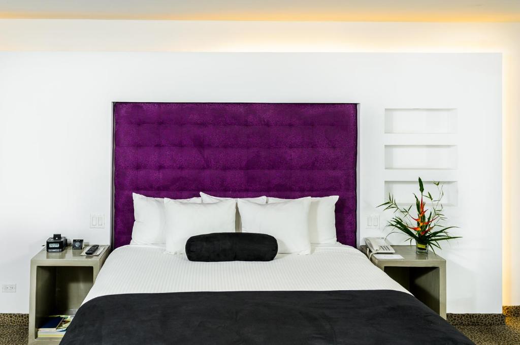 a bedroom with a large bed with a purple headboard at Riande Aeropuerto Hotel Casino in Tocumen