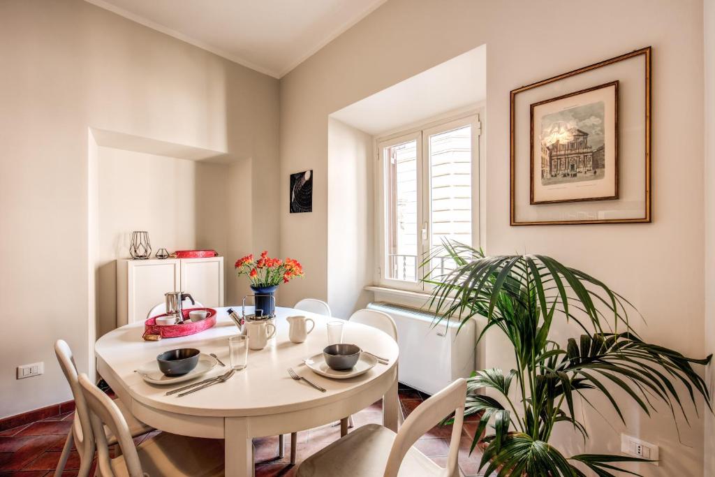 a dining room with a white table and a plant at Appartamento Via del Monte della Farina in Rome