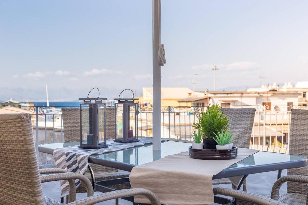 2 mesas y sillas en un balcón con vistas al océano en Spacious Maisonette - Roof Top View of Corfu Port, en Mantoúkion