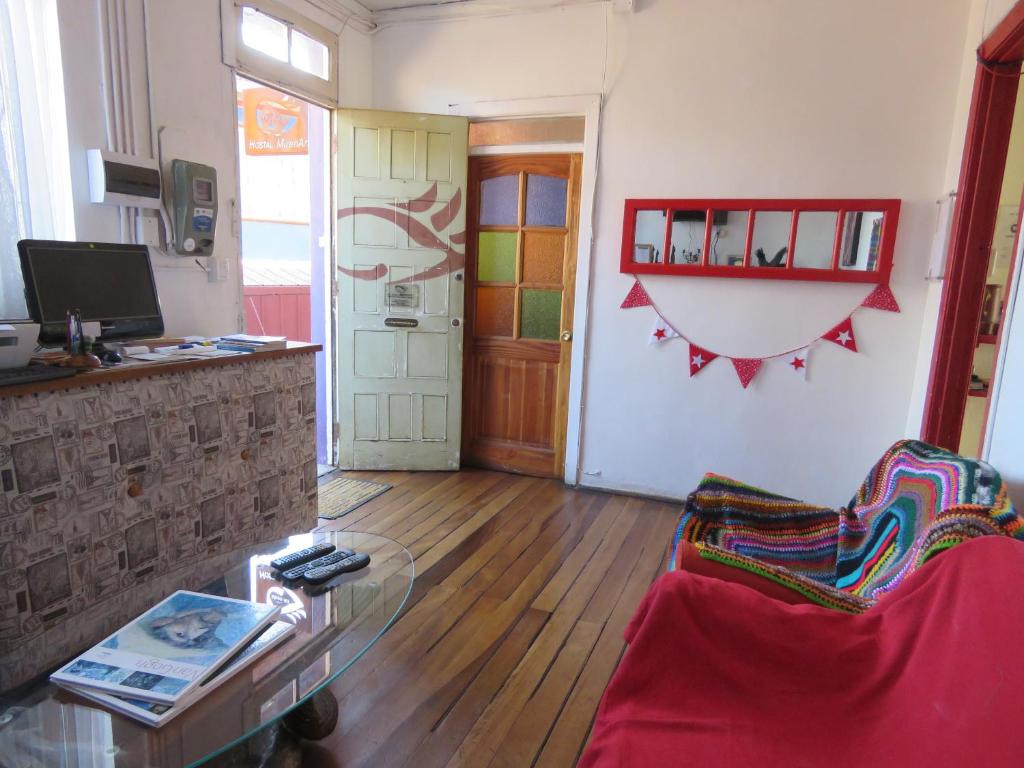 a living room with a red couch and a glass table at Hostal Mirenart in Valparaíso