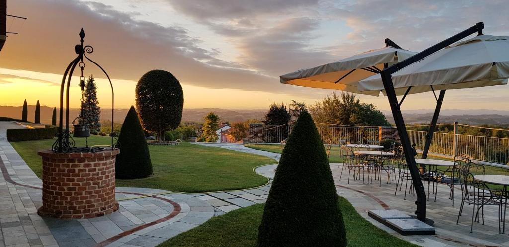 un patio con mesas, sillas y una sombrilla en B&B Cascina Bellavista, en Tigliole