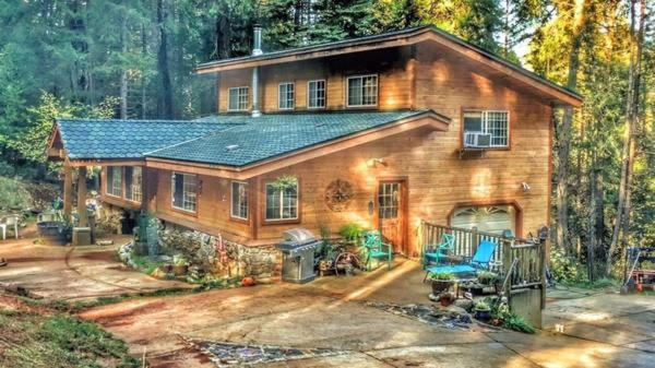 uma grande casa de madeira no meio de uma floresta em A Lovely Cabin House at Way Woods Retreat with Outdoor Hot Tub! - By Sacred Hub MGMT em Foresthill