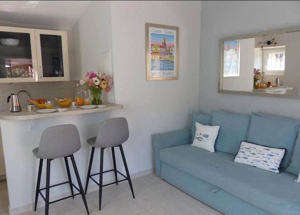 a living room with a blue couch and a kitchen at Charmante petite maison a l'éntrée de Saint Tropez in Saint-Tropez