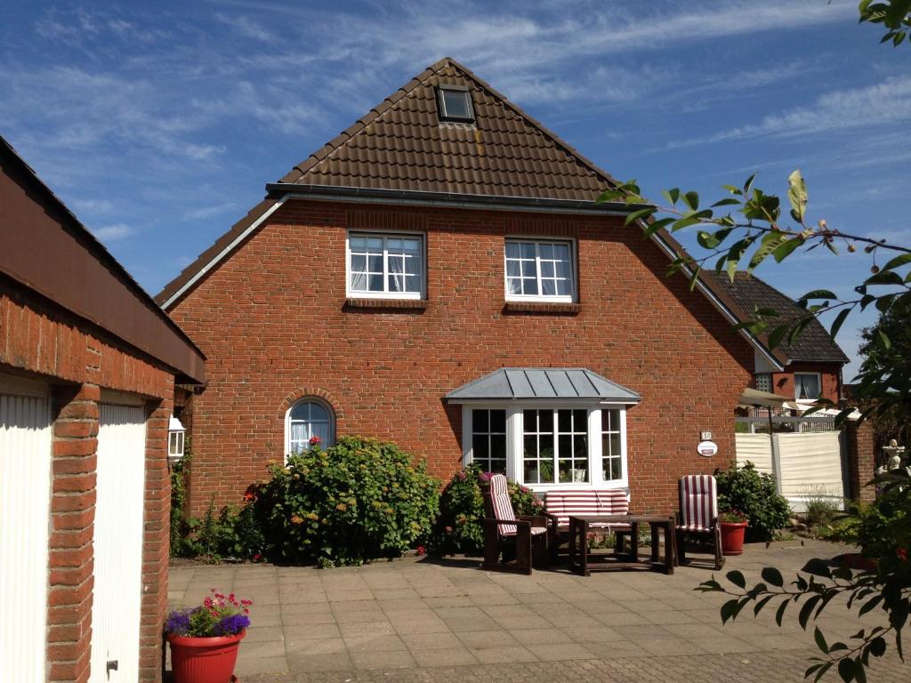 ein rotes Backsteinhaus mit 2 Stühlen und einem Tisch in der Unterkunft Appartement Vermietung Jensen in Morsum