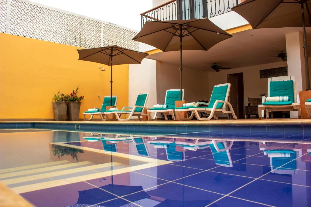 a swimming pool with blue chairs and umbrellas at La Gloria Hotel by BespokeColombia in Mompos