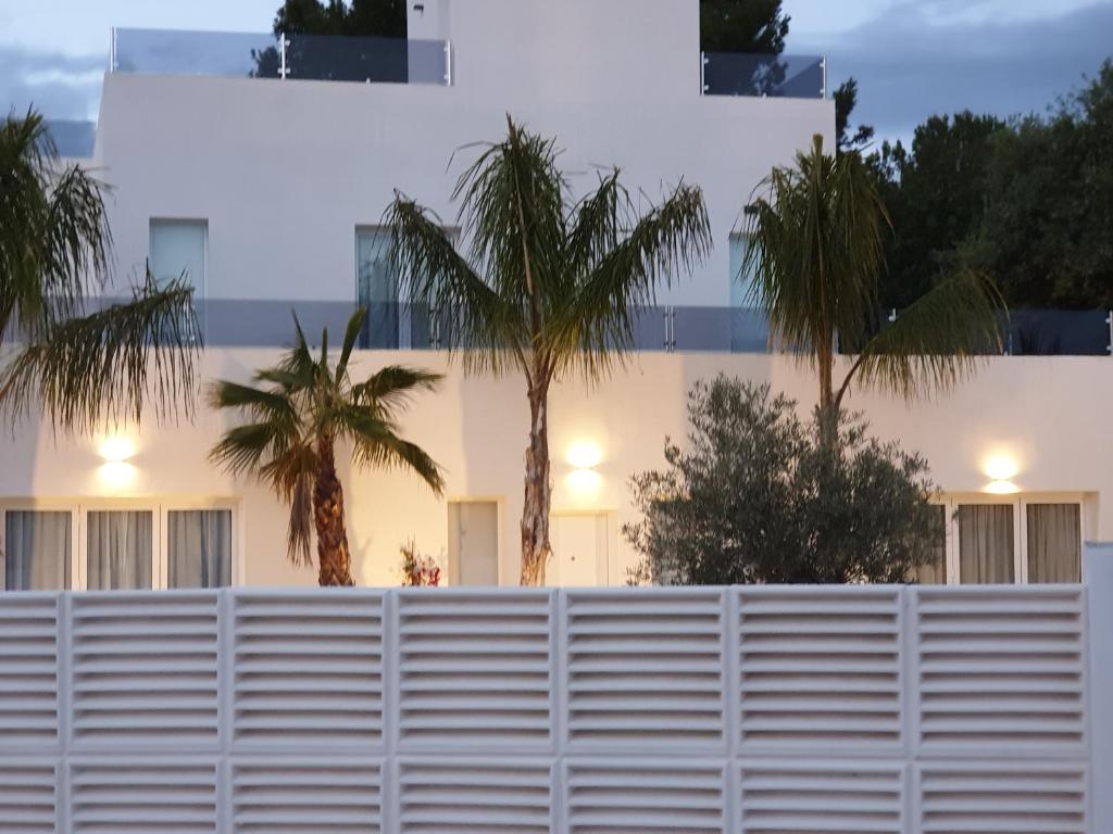 アロヨ・デ・ラ・ミエルにあるAMAZING VILLA By THE SEA BENALMADENAの建物前のヤシの木と白い柵