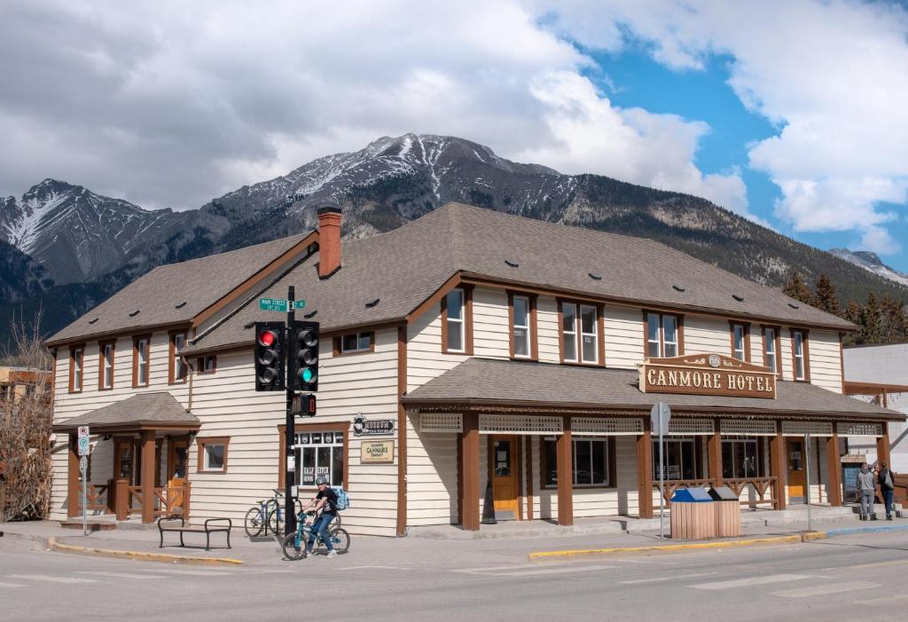 un edificio all'angolo di una strada con una montagna di PARTY HOSTEL - The Canmore Hotel Hostel a Canmore