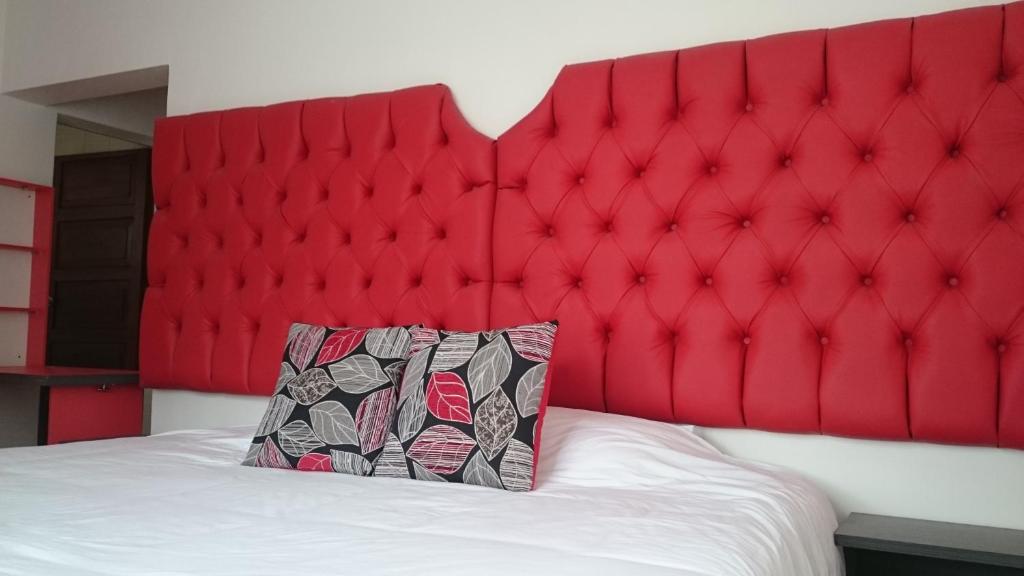 a red padded headboard with a pillow on a bed at Suites+Arte in Quito