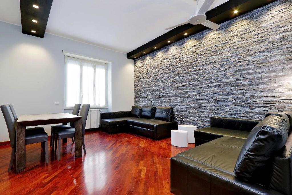 a living room with leather furniture and a brick wall at Sapphire Apartment in Rome
