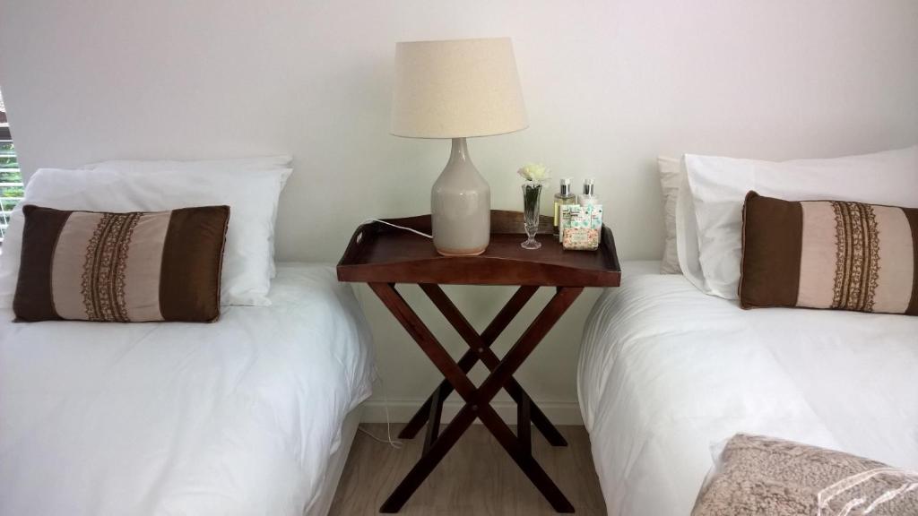 a table with a lamp on top of two beds at Milkwood House in Wilderness