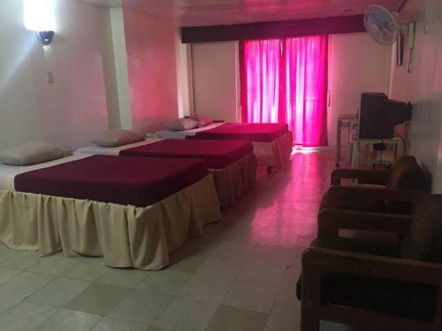 Habitación con 4 camas e iluminación rosa en Benguet Prime Hotel, en Baguio