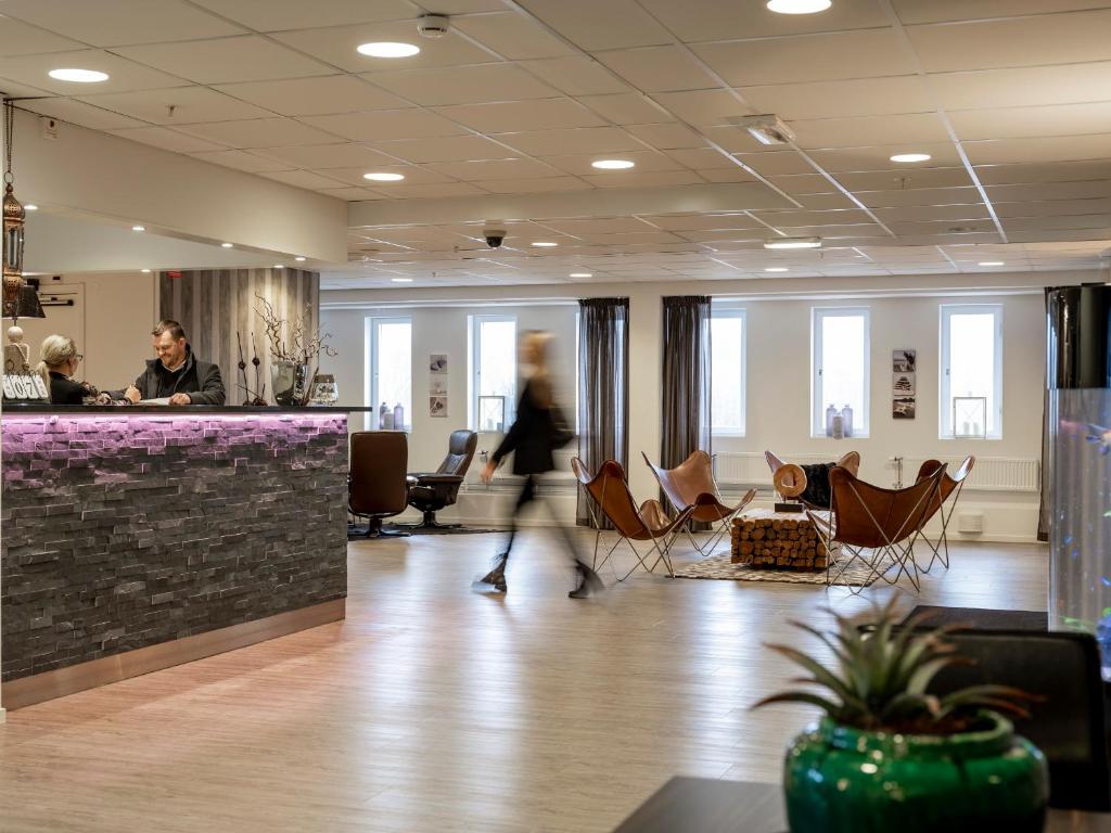a person walking through an office lobby with chairs and a counter at Slagsta Gate Hotell in Norsborg