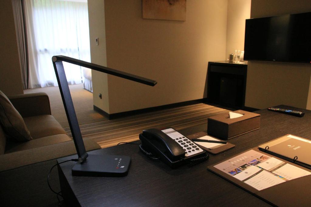 a room with a desk with a phone and a lamp at Platinum Hotel in Xindian