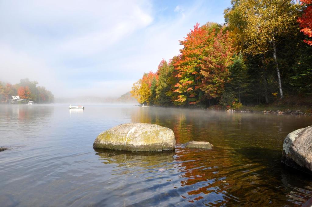 a rock in the middle of a lake with a boat at Le Boisé du Lac in Mont-Tremblant