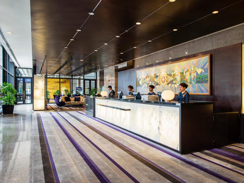 A bright reception lobby with a long marble-fronted check-in desk.