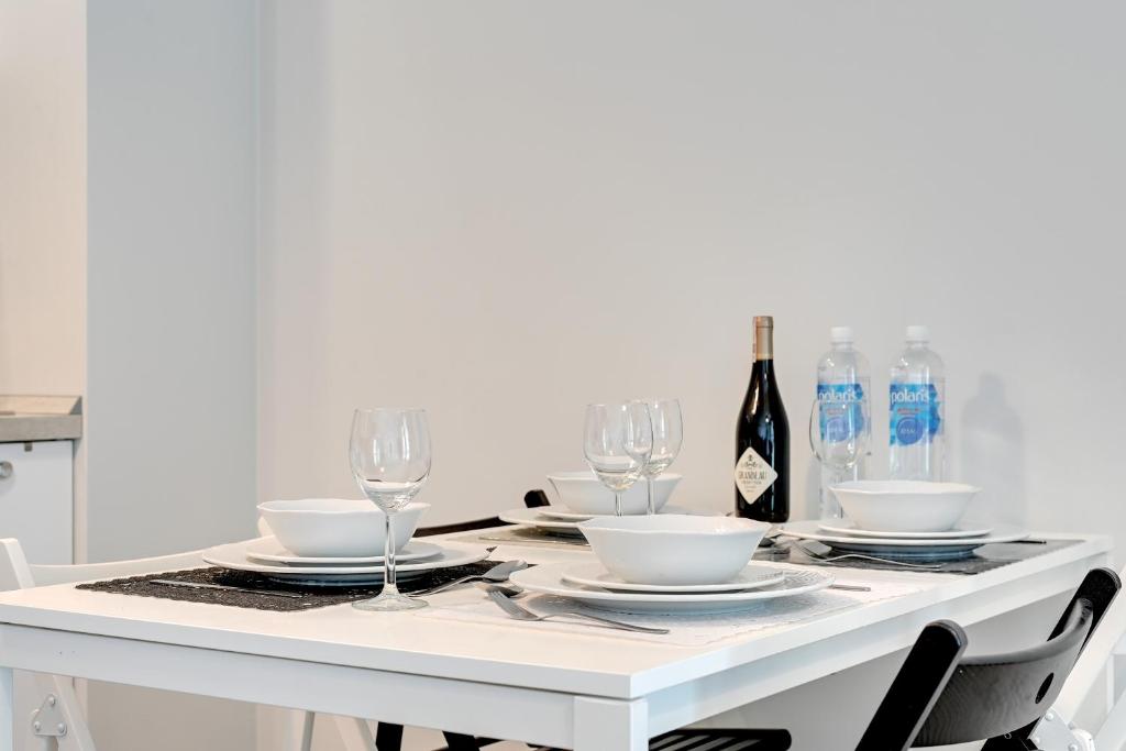 Biały stół z kieliszkami i butelką wina w obiekcie TriApart Amber Jantar II w mieście Jantar