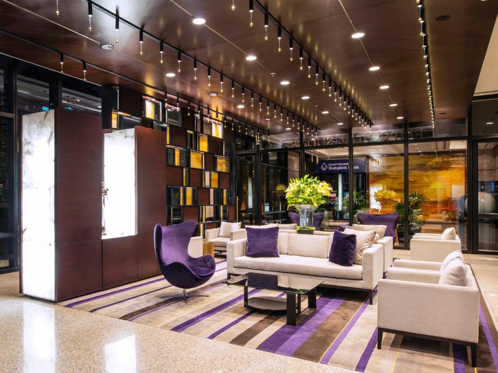 A polished lobby lounge with sofas, armchairs, bookshelves and warm lighting.