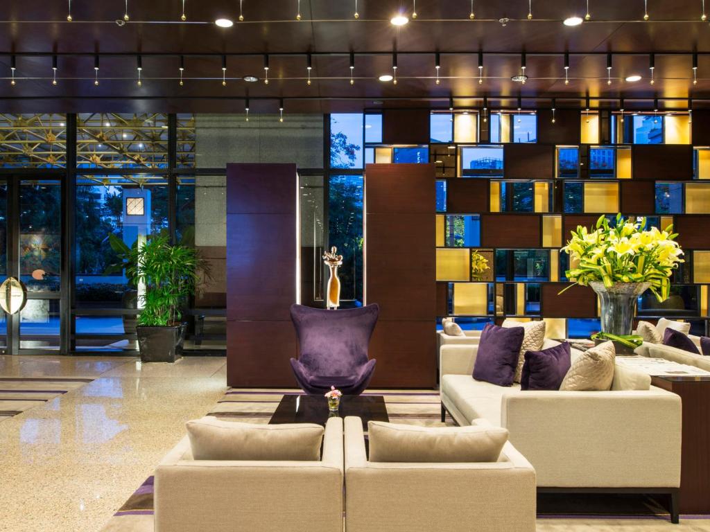 A spacious lobby lounge with sofas, plants, and illuminated display shelving.