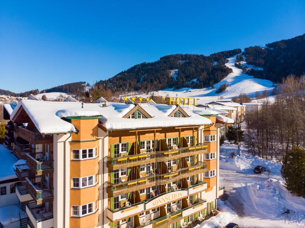 un hotel en las montañas con nieve en el techo en Harmony Hotel Sonnschein, en Niederau