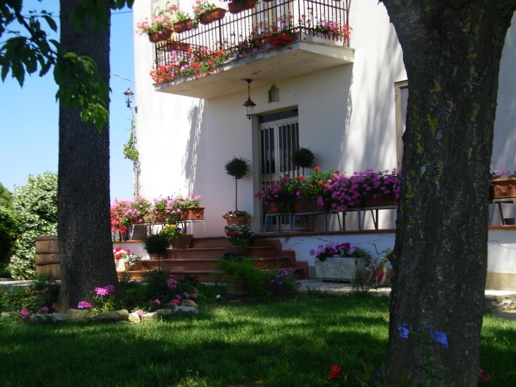 a white house with flowers on the balcony at B&B Casa Losea in Castello delle Forme