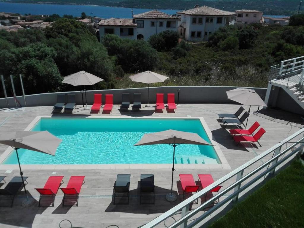 a swimming pool with red chairs and umbrellas at NRH Cannigione Sunrise Rooftop in Cannigione