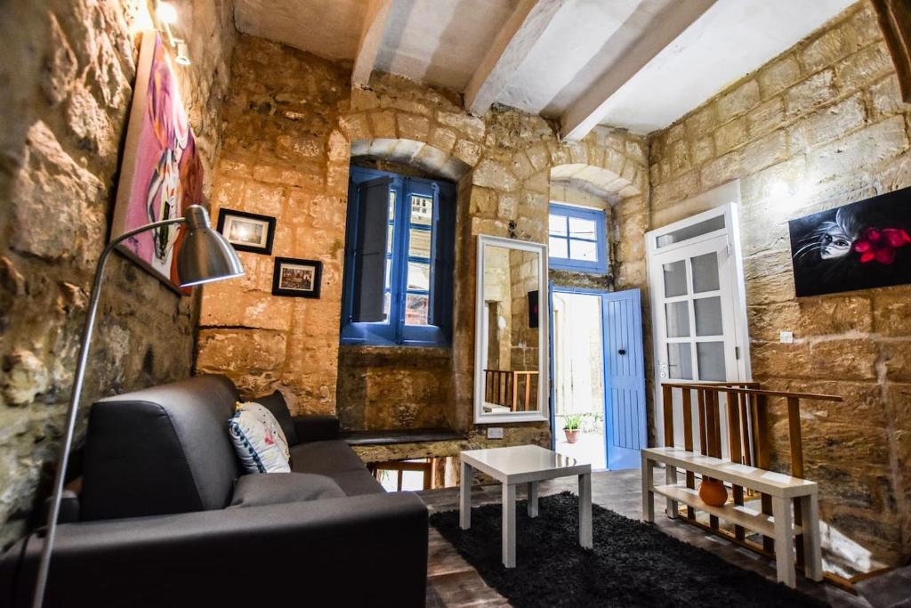 a living room with a couch and a stone wall at Historic Townhouse in Birgu Center in Vittoriosa