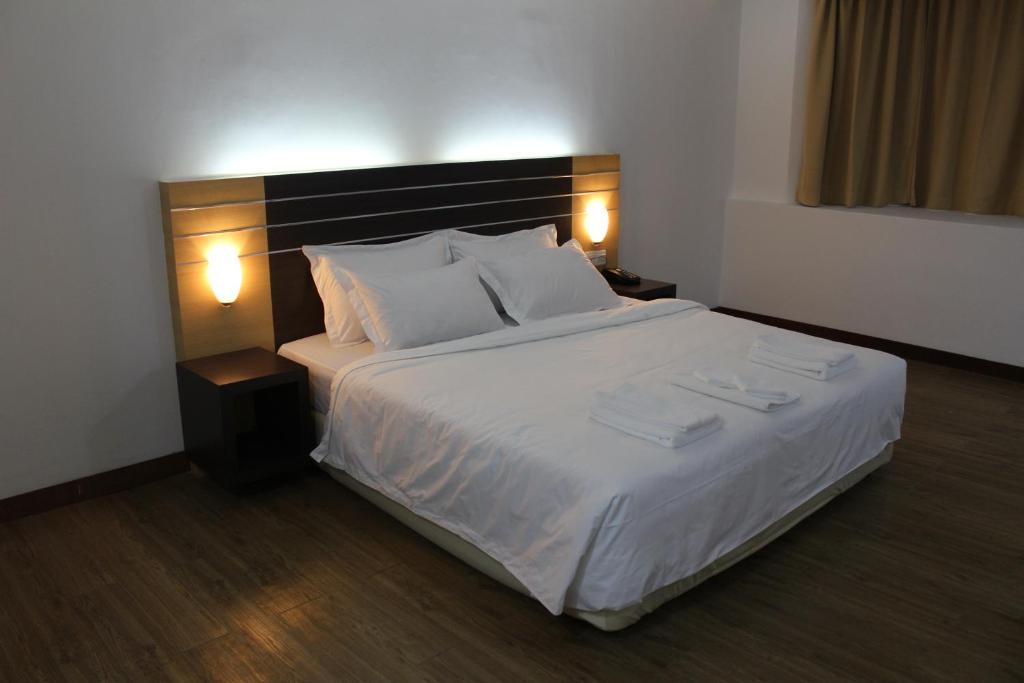 a bedroom with a large bed with white sheets and pillows at Sara Hotel in Labuan