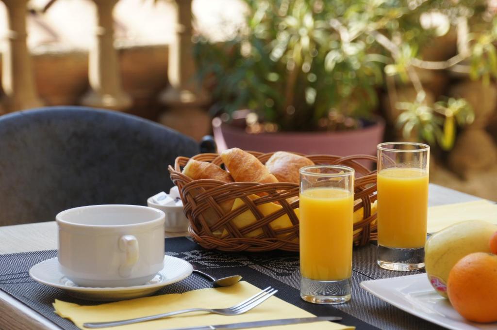 Hotel des Alpes في داي: طاولة مع سلة من الخبز وعصير البرتقال