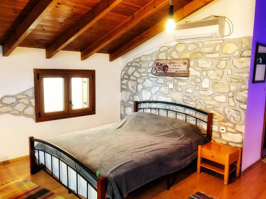1 dormitorio con 1 cama y pared de piedra en Romantic maisonette in the heart of Pythagoreio LH door, en Pythagoreio