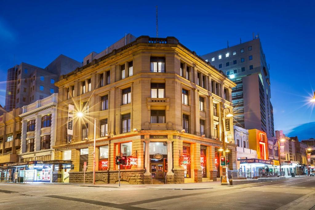 um edifício na esquina de uma rua da cidade à noite em Quest Savoy em Hobart