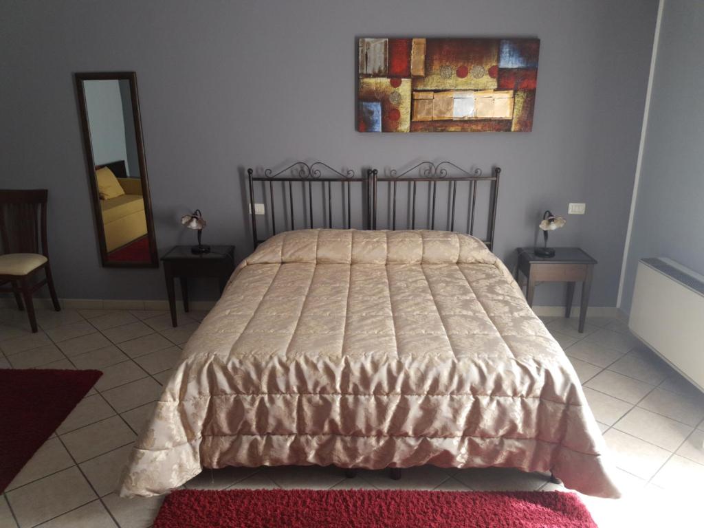 a bed in a bedroom with two tables and a mirror at Affittacamere La Piazzetta in Caltagirone