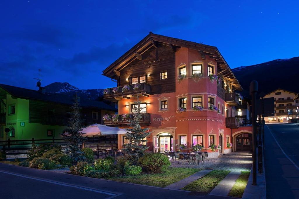 a large building with tables and chairs in front of it at Hotel Meeting in Livigno